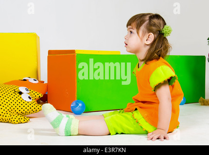 Little european girl is sitting among toys Stock Photo