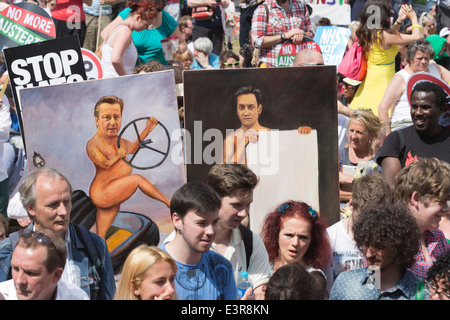 The No More Austerity demonstration & march takes place in Central London. Artist Kaya Mar holding up paintings of David Cameron and Ed Miliband. Stock Photo