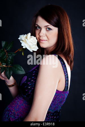 Beautiful caucasian girl holding white rose on black background Stock Photo