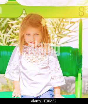 Portrait of cute little girl having fun on swing on play garden, preschooler spending summer holidays in the camp Stock Photo