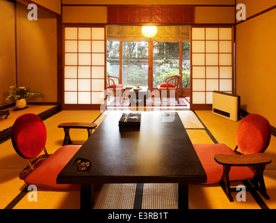 Japanese room interior at a ryokan with garden view in Kyoto, Japan. Tea table chabudai and zaisu chairs. Stock Photo