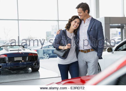 Couple hugging in car dealership showroom