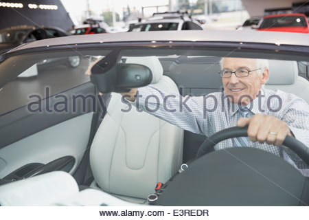 Man adjusting rear-view mirror in showroom convertible