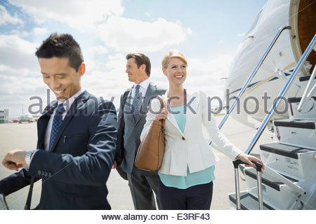 Business people on tarmac with corporate jet