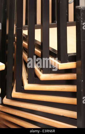 Inverted upside down stacked metal tables deck legs making a pattern of bars spiraling upwards at corners Stock Photo