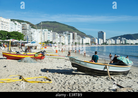 RIO DE JANEIRO, BRAZIL - FEBRUARY 04, 2014: Brazilian fishing boats share the beach with walkers on tranquil morning Copacabana Stock Photo