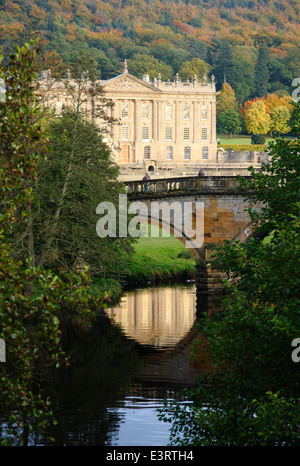 The River Derwent flows by Chatsworth House stately home viewed from open access parkland, Peak District, England, UK - autumn Stock Photo