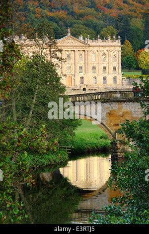 The River Derwent flows by Chatsworth House stately home viewed from open access parkland, Peak District, England, UK - autumn Stock Photo