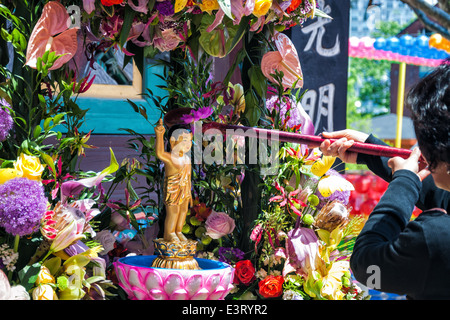 A Buddhist woman pours water over a small Buddha statue at Jogyesa Temple on May 5, 2014 in Seoul, South Korea. Stock Photo