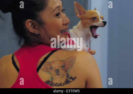 Manila, Philippine. 28th June, 2014. MANILA, Philippines - A woman with a portrait of her dog tattooed on her back prepares to have her dog's photo taken as hundreds of pet lovers join a Dog and Cat Expo held at a Convention Center in Pasay city, south of Manila on 28 June 2014. Now on its third year, the Pet Express Dog and Cat EXPO attracts thousands of dog and cat lovers of all ages as they hold this 2-day event, with various activities for the animals and their owners to participate in. The event aims to give the canine and feline community a venue to meet like-minded people and to learn Stock Photo