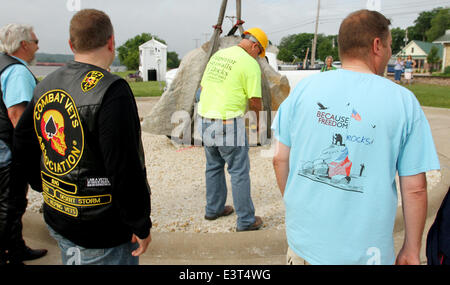 Le Claire, IOWA, USA. 28th June, 2014. Local residents watch as crews with Superior Seawalls and Docks work to put the The Scott County Freedom Rock in place on the river front in LeClaire, Iowa on Saturday, June 28, 2014. The original Freedom Rock is a large (approx. 60 ton) boulder located in rural Iowa that is repainted every year with a different Thank You for our nations Veterans to honor their service to our country. The artist, Ray ''Bubba'' Sorensen II, was inspired by the movie Saving Private Ryan, as well as, wanting to give Veterans a unique recognition on Memorial Day. With 99 co Stock Photo