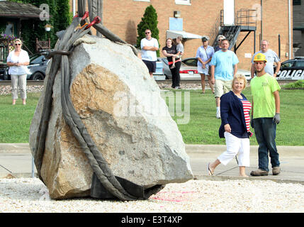 Le Claire, IOWA, USA. 28th June, 2014. Local residents watch as crews with Superior Seawalls and Docks work to put the The Scott County Freedom Rock in place on the river front in LeClaire, Iowa on Saturday, June 28, 2014. The original Freedom Rock is a large (approx. 60 ton) boulder located in rural Iowa that is repainted every year with a different Thank You for our nations Veterans to honor their service to our country. The artist, Ray ''Bubba'' Sorensen II, was inspired by the movie Saving Private Ryan, as well as, wanting to give Veterans a unique recognition on Memorial Day. With 99 co Stock Photo