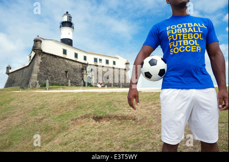 Brazilian footballer in international football shirt standing with soccer ball at the Farol da Barra lighthouse Salvador Brazil Stock Photo