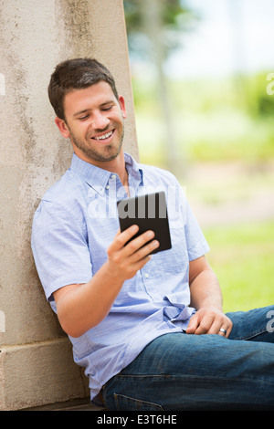 Young man reading E-book outside on steps Stock Photo