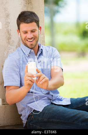 Young man using cell phone and head phones outside Stock Photo