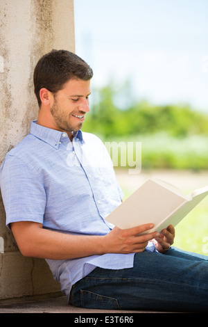 Young man reading book outside on steps Stock Photo
