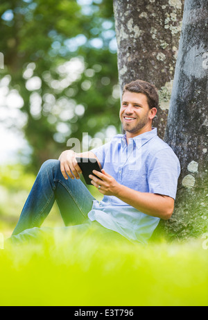 Young man reading E-Book outside in park Stock Photo