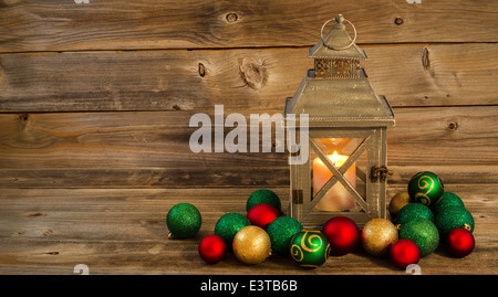 old Asian design lantern and white candle glowing brightly inside with Christmas Ornaments on rustic wood Stock Photo