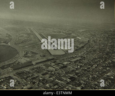 This aerial photograph shows the Consolidated/Convair aircraft factory and Lindbergh Field in San Diego. The factory, known for producing bombers and other military aircraft, played a significant role in aviation during and after WWII. The photo highlights both the factory's scale and its proximity to the airport. Stock Photo