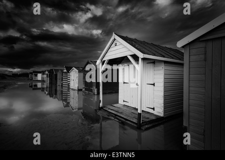 Black and white rendition of beach huts on the sandy beach of West Wittering, West Sussex, UK Stock Photo