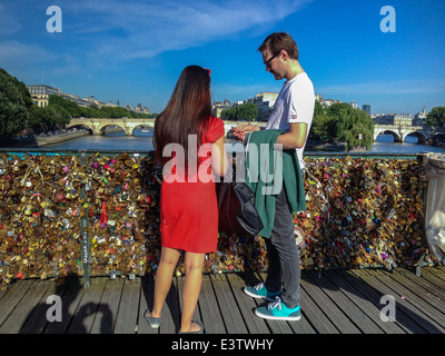 Paris, France, Tourist Couple on Seine River Bridge, 'Pont des Arts' with Love Locks, Woman Standing in Red Dress, European weekend getaway Holidays Stock Photo