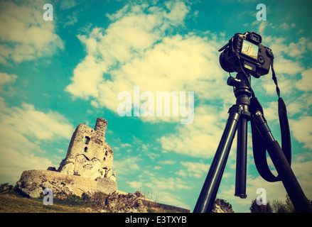 Camera on tripod with summer landscape with ruins, vintage retro style. Stock Photo