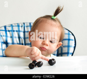 Baby in highchair playing with food Stock Photo