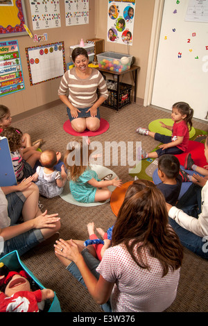 Mothers and their young children attend a 'Learning Link' classroom in Tustin, CA, where a Hispanic teacher conducts a workshop in interactive behavior. Using specially designed activities, the class teaches parents how to engage their children in meaningful play. Stock Photo