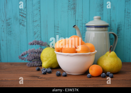Apricots in bowl with fresh pear and blueberry on wooden background Stock Photo
