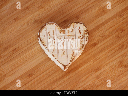 Neufchatel cheese shaped like heart on wooden cutting board Stock Photo