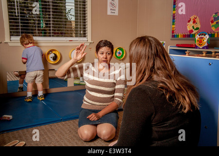 A Hispanic teacher advises a mother as her son plays at a "Learning Link" classroom in Tustin, CA, conducting a workshop in interactive behavior. Using specially designed activities, the class teaches parents how to engage their children in meaningful play. Stock Photo
