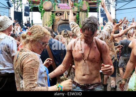 Glastonbury, Somerset, UK. 29th June 2014. Glastonbury Festival, 29th June, 2014: Tomato pulp mixed with the mud covering hundreds of people taking part in a giant tomato fight. The fight was held in the Temple venue, which is part of the 'Common' in the south east part of the festival site Credit:  Tom Corban/Alamy Live News Stock Photo