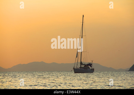 Sailing yaht in open sea on beautiful sunset sky background Stock Photo