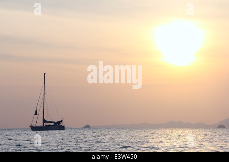 Sailing yaht in open sea on beautiful sunset sky background Stock Photo