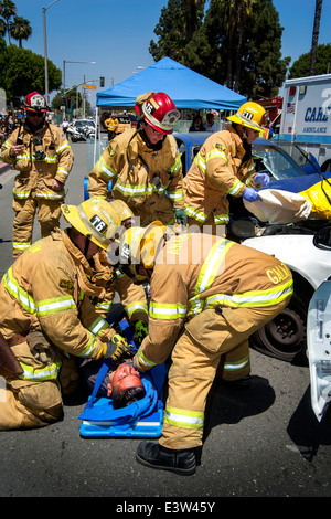 Anaheim, CA, paramedic firemen aid a volunteer 'victim' from a smashed car involved in a dramatization of a traffic accident to show high school students the dangers of drunk driving. Note ambulance at right. Stock Photo