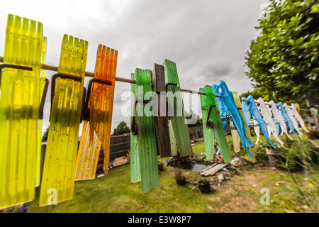 Looks like rain. Mixture of clothes pegs on empty washing line. Wooden and plastic pegs. Old and new pegs. Stock Photo