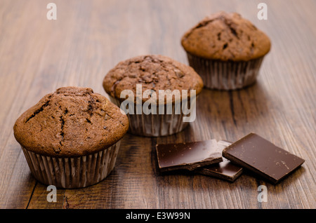Three Muffins with dark chocolate on a wooden table Stock Photo