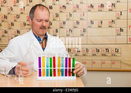 Chemist filling glass test tubes with colored liquids Stock Photo