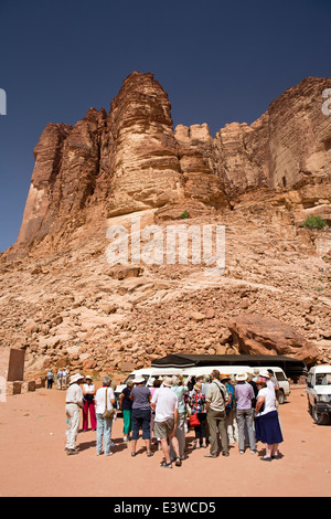 Jordan, Wadi Rum, group of western tourists at base of eroded rocky desert cliffs Stock Photo
