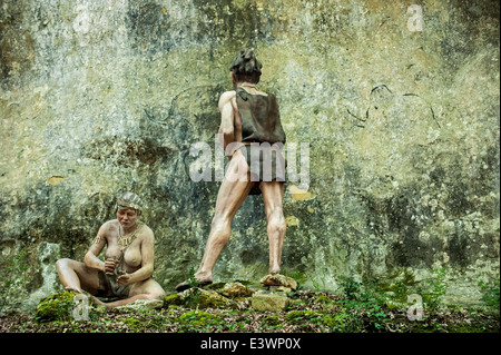 Cro-Magnon woman and man painting animals on rock face at Prehisto Parc about prehistoric life at Tursac, Dordogne, France Stock Photo