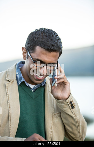 Ethnic man with glasses laughing with smartphone. Stock Photo