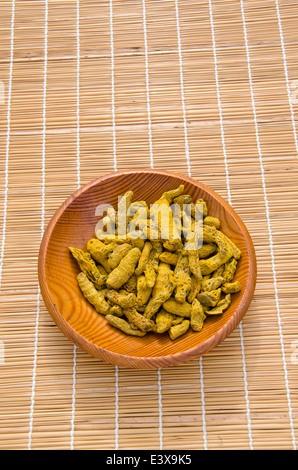 turmeric (Curcuma longa) dry roots in wooden plate on table Stock Photo