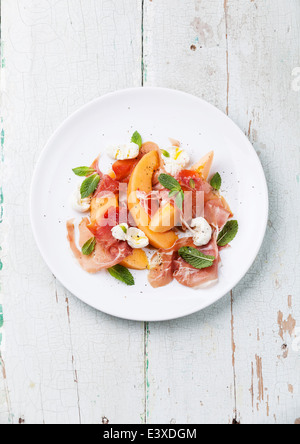 Melon and prosciutto ham salad with Mozzarella and mint leaves Stock Photo