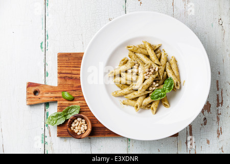 Pasta Penne with pesto sauce and pine nuts on wooden background Stock Photo