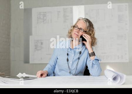 Caucasian architect talking on phone at desk Stock Photo