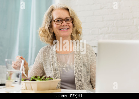 Senior Caucasian businesswoman eating salad Stock Photo