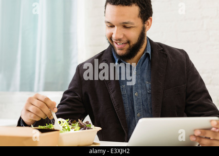 Mixed race businessman eating salad Stock Photo