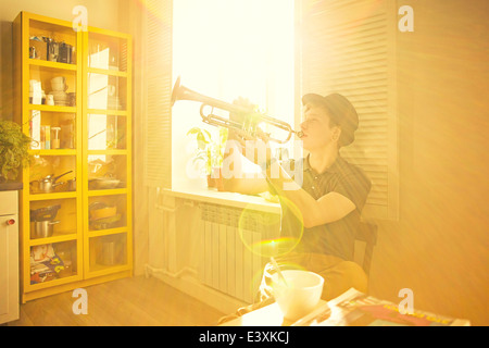 Caucasian man playing trumpet in kitchen Stock Photo