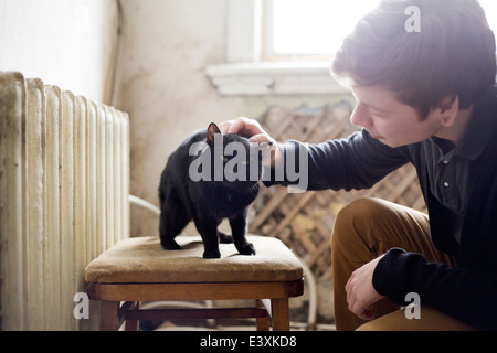 Caucasian man petting cat in living room Stock Photo