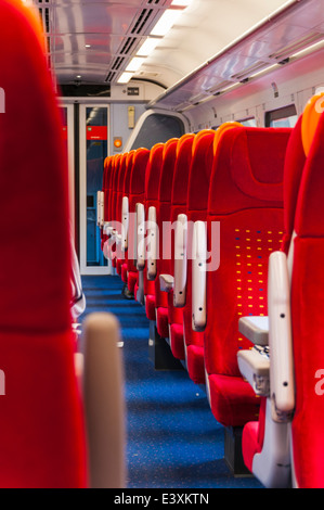 Looking along the rows of red seats on the inside of a passenger carriage operated by East Midland Trains Stock Photo